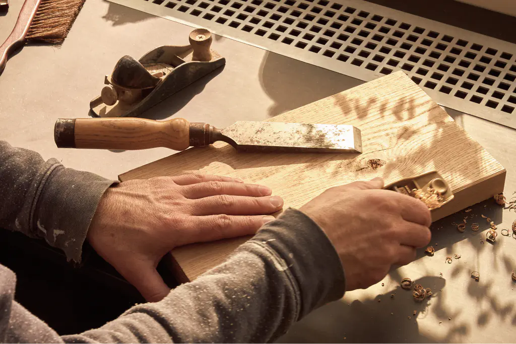 Woodworking instructor demonstrating how to shave wood with a vintage hand plane.