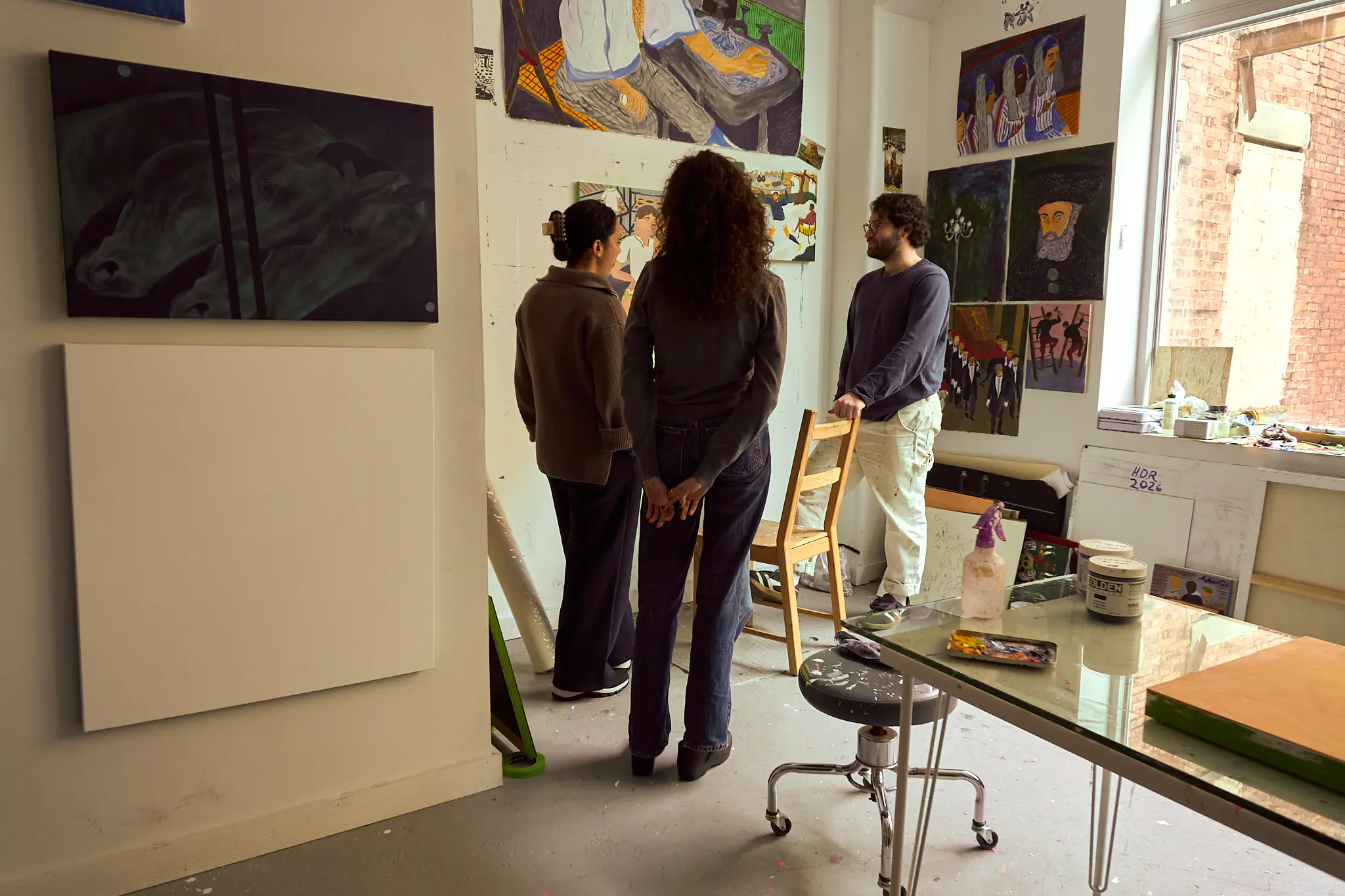 Teaching artist and students reviewing artwork in a naturally lit studio.