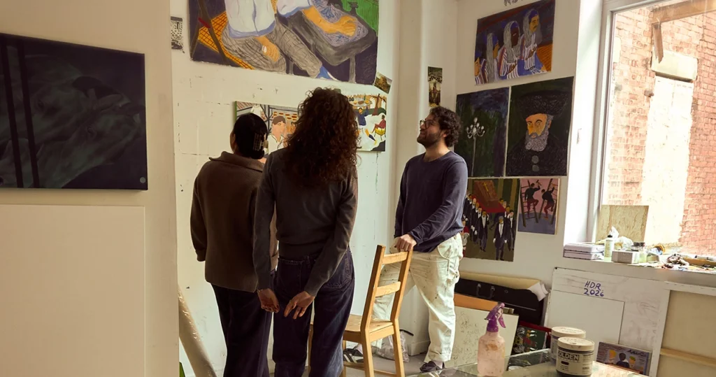 Artist and students discussing artwork together in a painter’s studio.