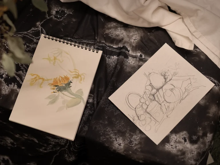 Sketchbooks with watercolor and drawn still-life studies in progress.